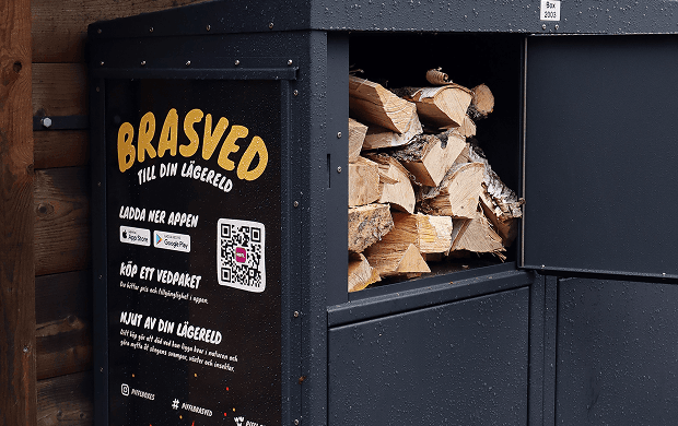 Piffl Brasved – Hållbar ved tillgänglig dygnet runt Piffl Brasved-box med öppet fack där ved syns redo att köpas