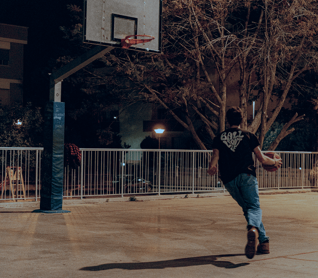 Evening Basketball – Play whenever you want with Piffl's activity boxes A man playing basketball on an illuminated basketball court late in the evening